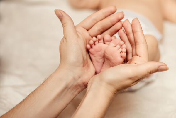 Bild vergrößern: Mutterhände und Babyfüße