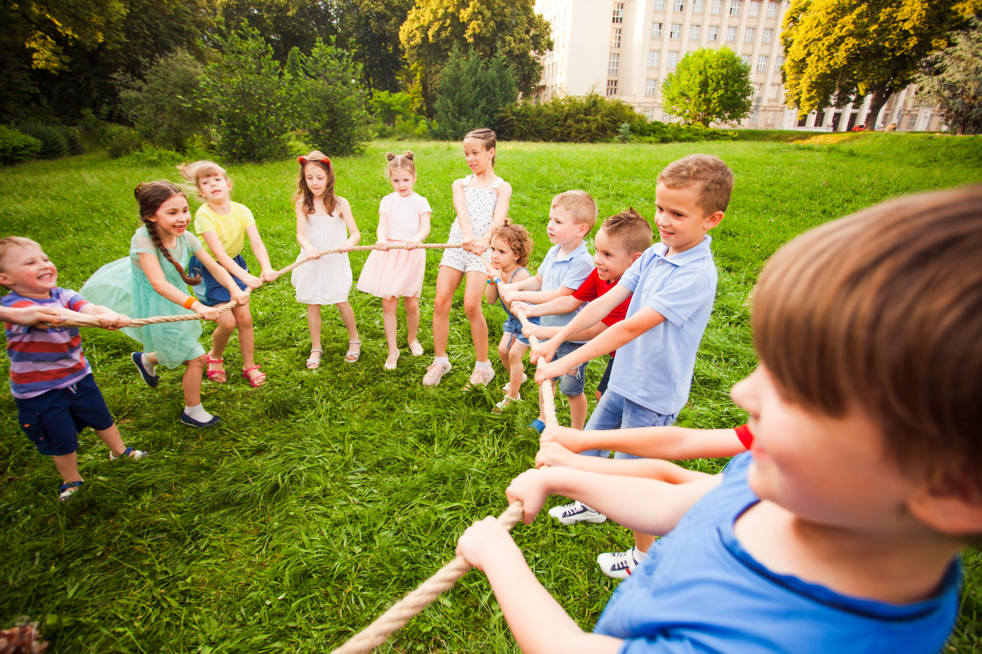 Kinder jeden Alters bilden im Freien einen Seilkreis. 