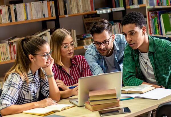 Bild vergr&ouml;&szlig;ern: Vier junge Schüler lernen in der Schulbibliothek, sie nutzen Laptops