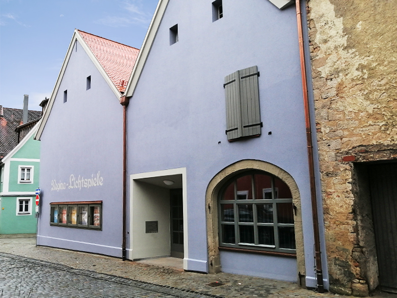 Bild vergrößern: Lilas Haus mit großem Eingang. An der Fassade hängen Plakate mit verschiedenen Theaterangeboten.