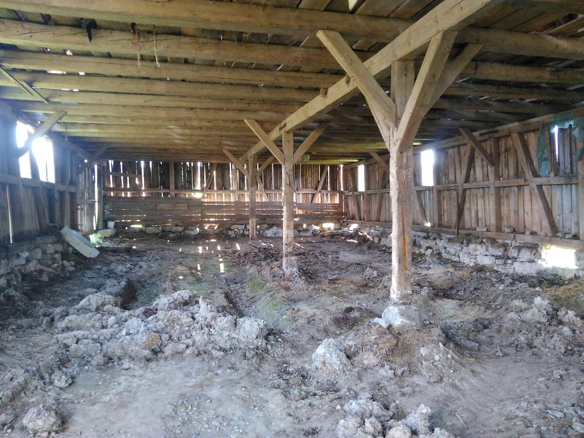 Bild vergrößern: Alte Schule mit Holzwänden und Holzdecke. Der Erdboden ist sehr uneben.