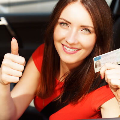 Frau zeigt Führerschein und hebt den Daumen