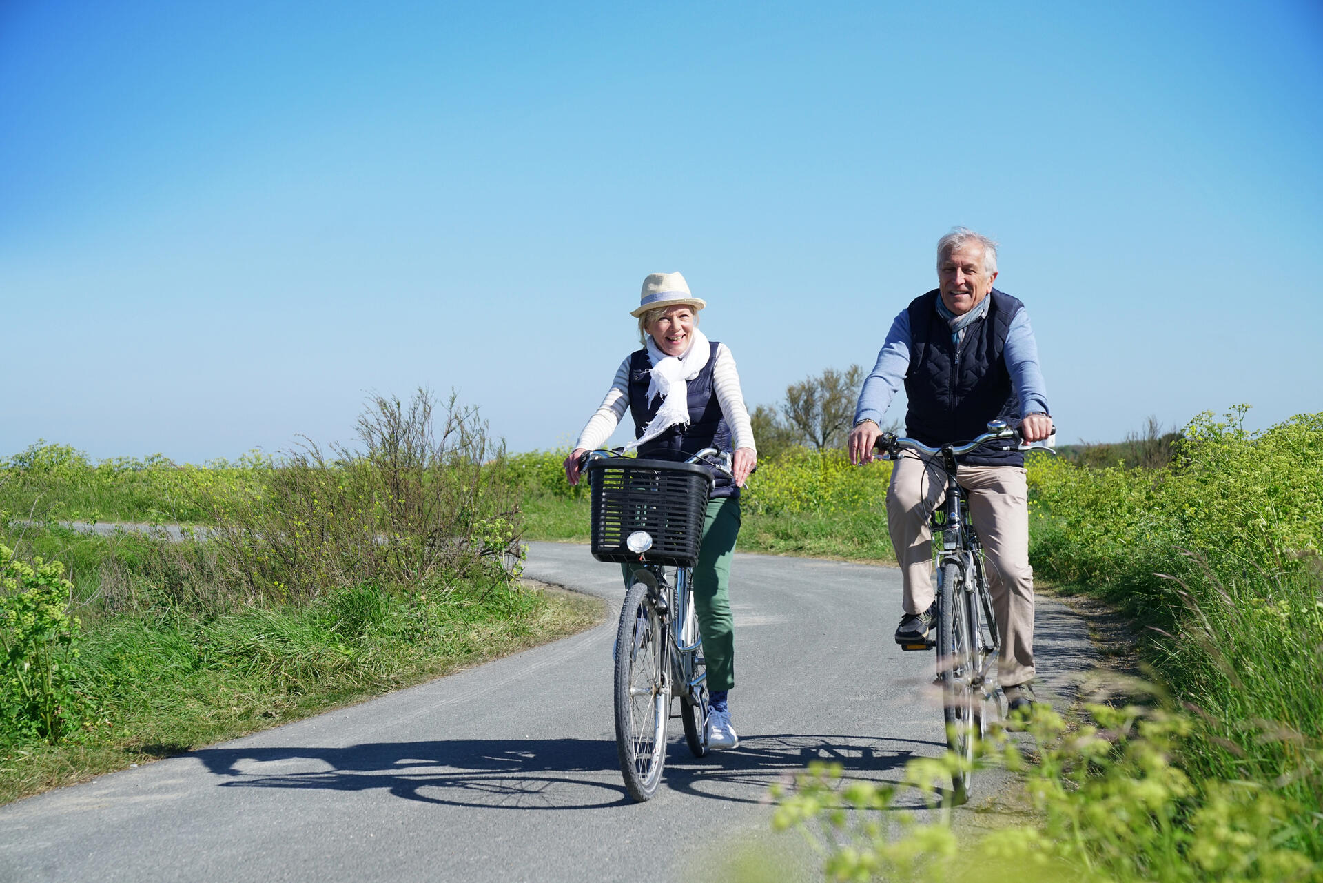 Älteres Paar, das zusammen Fahrrad auf der Landstraße fährt